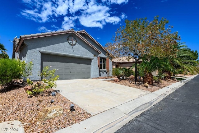 view of front of house featuring a tile roof, an attached garage, driveway, and stucco siding