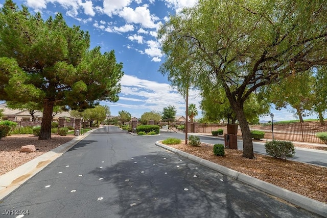 view of road with curbs, a gated entry, and a gate