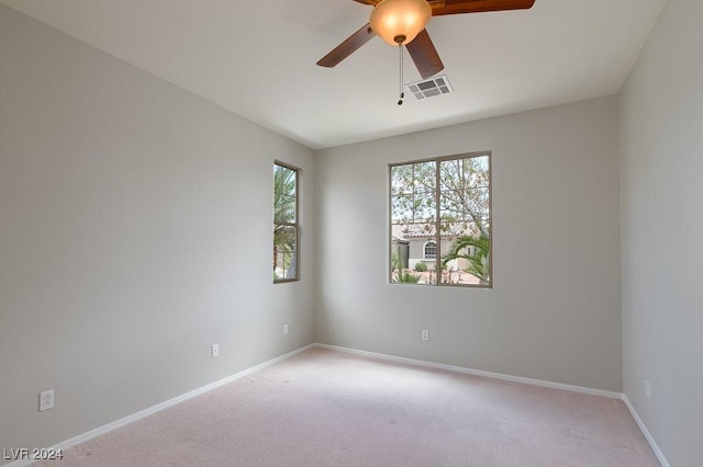 spare room featuring visible vents, light carpet, baseboards, and a ceiling fan