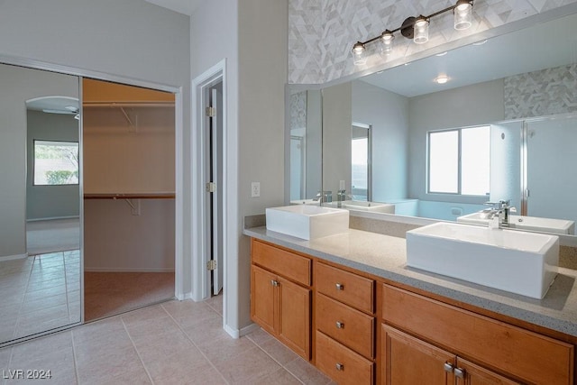 bathroom featuring a sink, a spacious closet, tile patterned floors, and double vanity