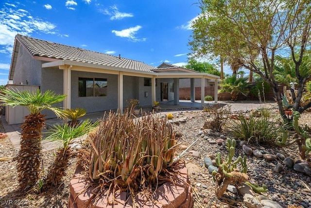 rear view of house with a tile roof and stucco siding