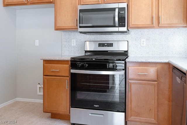 kitchen featuring baseboards, tasteful backsplash, appliances with stainless steel finishes, and light tile patterned flooring