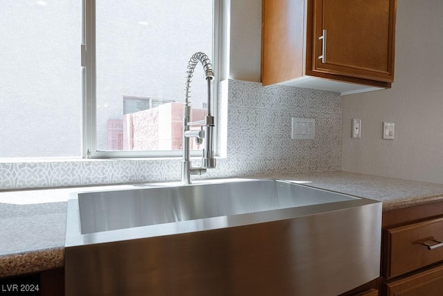 details featuring brown cabinetry, backsplash, and a sink