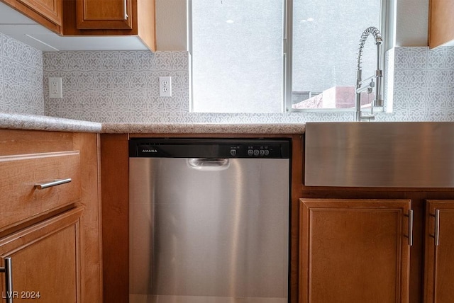 kitchen featuring a sink, backsplash, dishwasher, and brown cabinetry