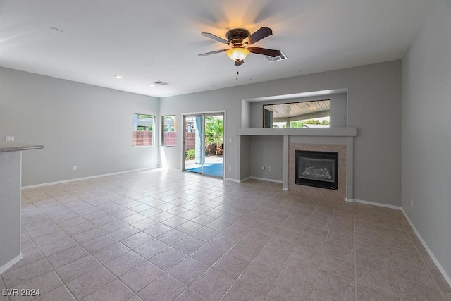 unfurnished living room with a tiled fireplace, light tile patterned floors, a ceiling fan, and visible vents