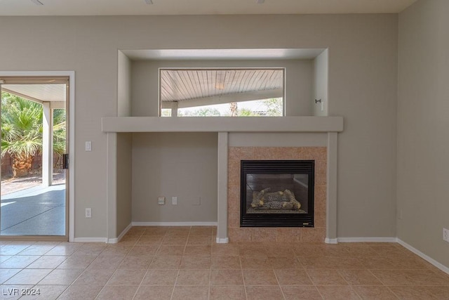 unfurnished living room with light tile patterned floors, baseboards, and a tiled fireplace