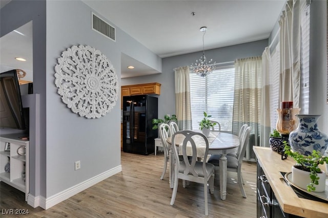 dining space with light hardwood / wood-style flooring and a chandelier