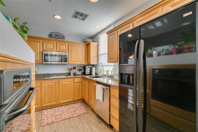 kitchen featuring light stone countertops, sink, light wood-type flooring, and stainless steel appliances