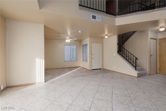 unfurnished living room with ceiling fan, a towering ceiling, and light tile patterned flooring