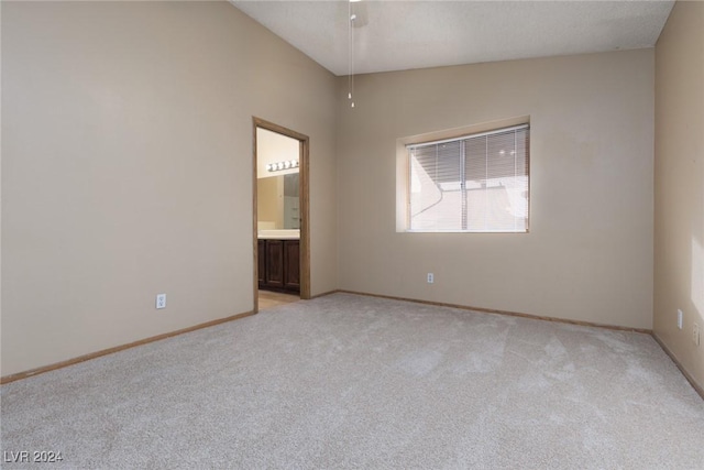 spare room featuring light colored carpet and vaulted ceiling