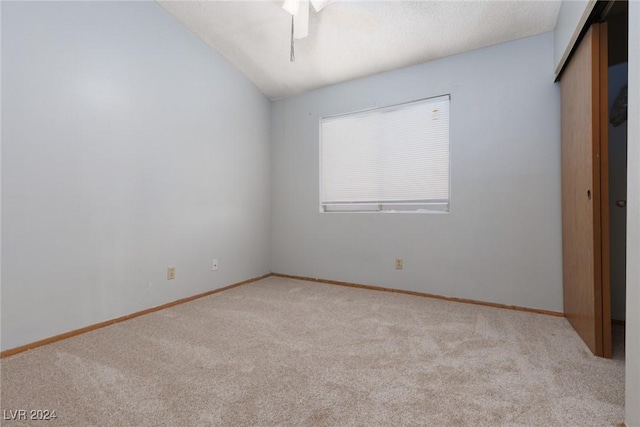 unfurnished bedroom with light colored carpet, vaulted ceiling, and ceiling fan