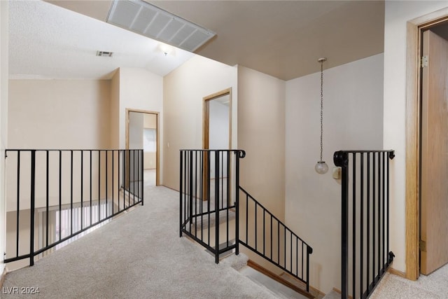 hall featuring light colored carpet and lofted ceiling