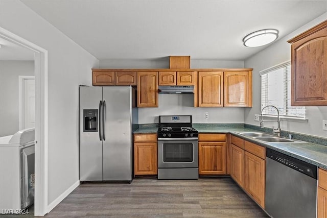 kitchen featuring appliances with stainless steel finishes, dark hardwood / wood-style flooring, washer / dryer, and sink