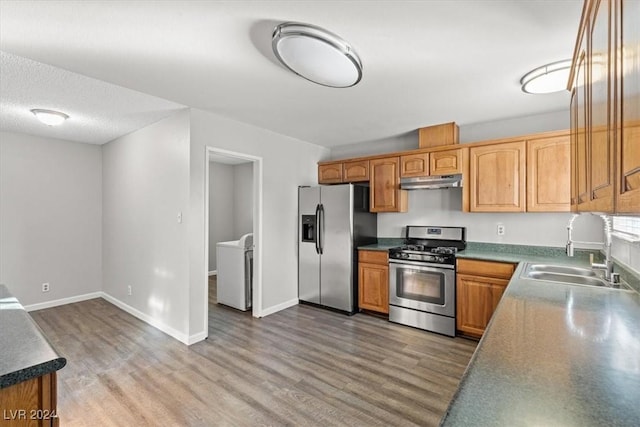 kitchen with sink, wood-type flooring, a textured ceiling, and appliances with stainless steel finishes