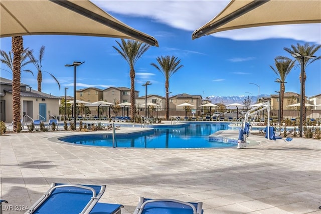 community pool with a patio, fence, and a residential view