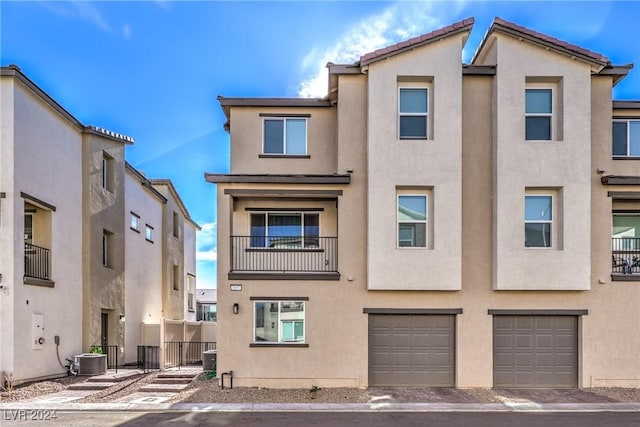 multi unit property with fence, central AC, stucco siding, a garage, and a tile roof