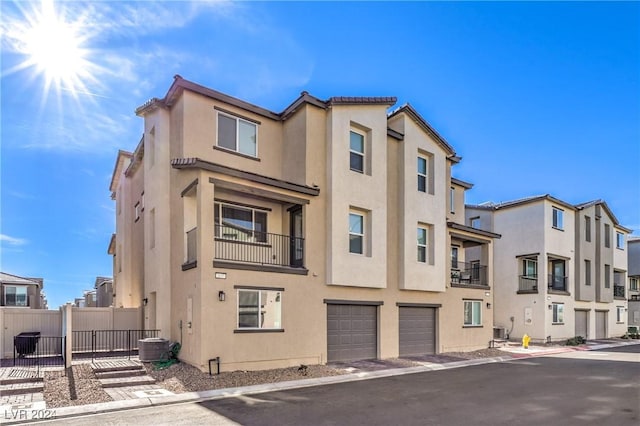 view of building exterior with an attached garage, fence, a residential view, and cooling unit