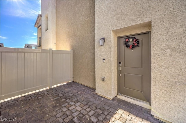 property entrance featuring stucco siding and fence