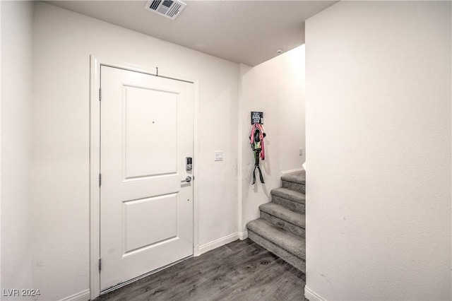 entryway with dark wood finished floors, visible vents, stairs, and baseboards