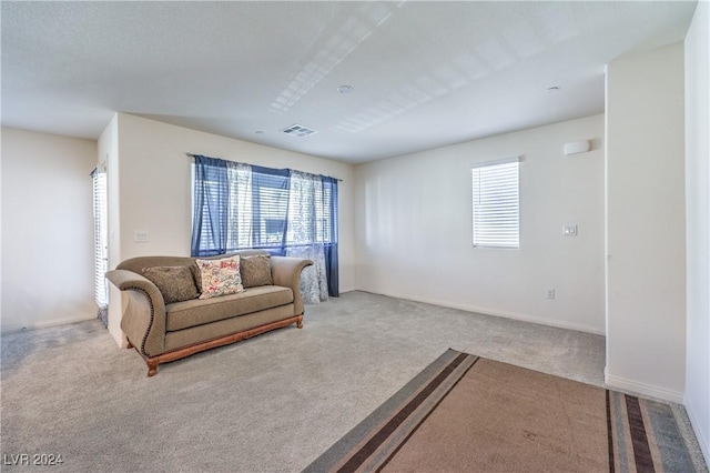 carpeted living area featuring a wealth of natural light, visible vents, and baseboards