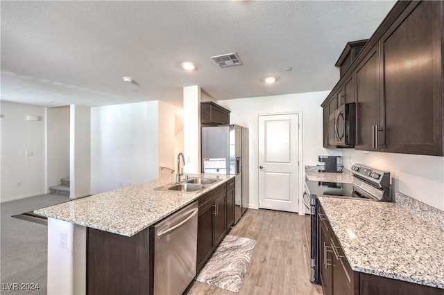 kitchen featuring visible vents, a sink, appliances with stainless steel finishes, light stone countertops, and dark brown cabinets