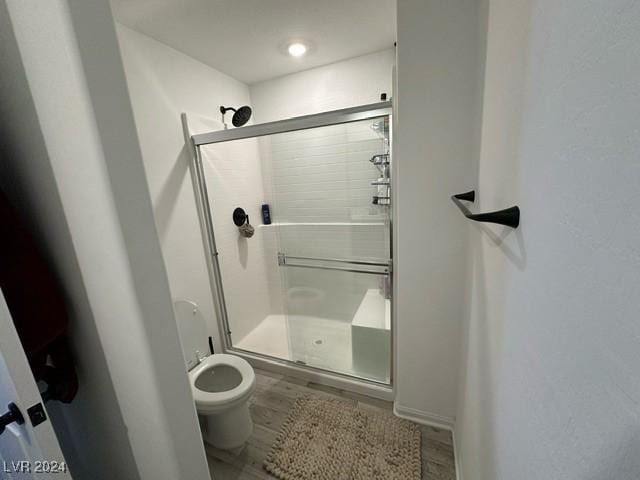 full bathroom featuring toilet, a shower stall, and wood finished floors