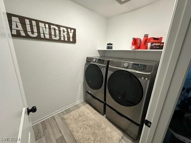 washroom featuring laundry area, baseboards, separate washer and dryer, and wood finished floors