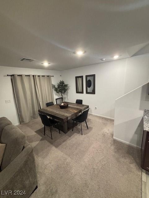 dining room featuring light colored carpet, visible vents, and baseboards