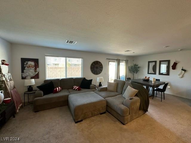 living area featuring light colored carpet, visible vents, and a textured ceiling