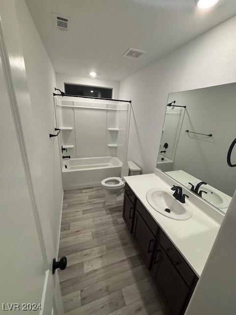 bathroom featuring visible vents, toilet, washtub / shower combination, vanity, and wood finished floors