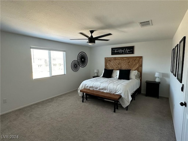 carpeted bedroom featuring visible vents, ceiling fan, and a textured ceiling