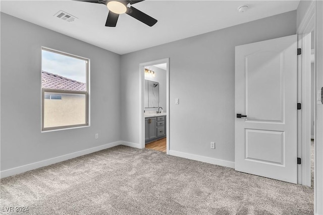 unfurnished bedroom featuring ensuite bathroom, ceiling fan, light colored carpet, and sink