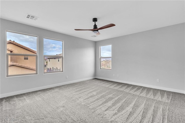 unfurnished room featuring a wealth of natural light, carpet floors, and ceiling fan