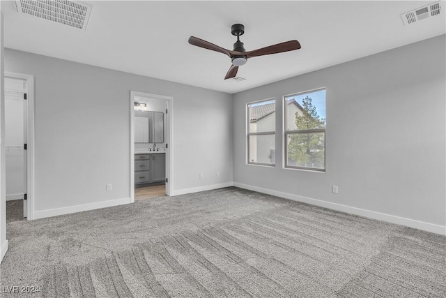 unfurnished bedroom with connected bathroom, light colored carpet, and ceiling fan