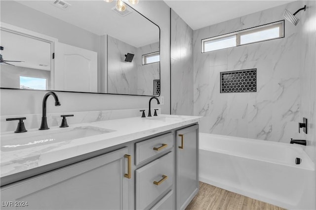 bathroom with vanity, a healthy amount of sunlight, wood-type flooring, and tiled shower / bath