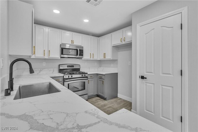 kitchen with white cabinetry, sink, light stone countertops, and stainless steel appliances