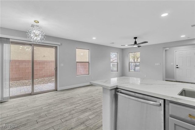 kitchen featuring light stone counters, hanging light fixtures, stainless steel dishwasher, and ceiling fan with notable chandelier