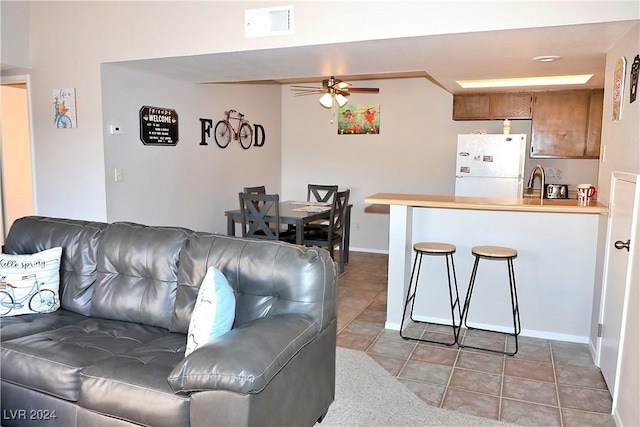 living room featuring ceiling fan, light tile patterned flooring, and sink