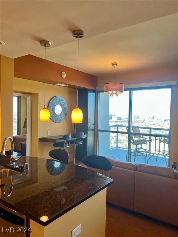 kitchen with pendant lighting, dark stone countertops, and sink