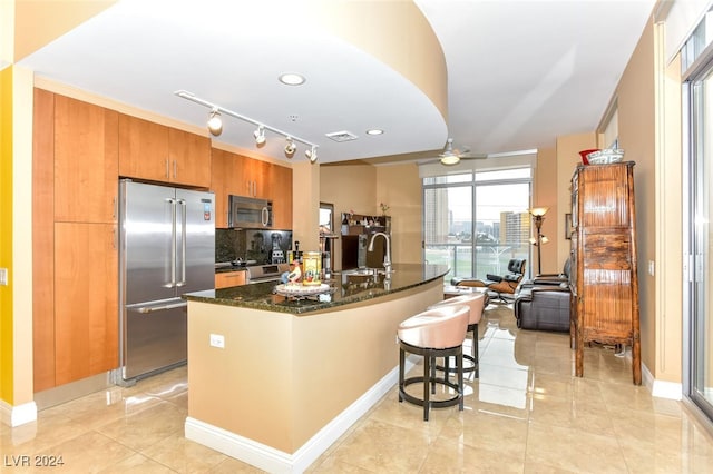 kitchen featuring a kitchen bar, appliances with stainless steel finishes, decorative backsplash, ceiling fan, and sink