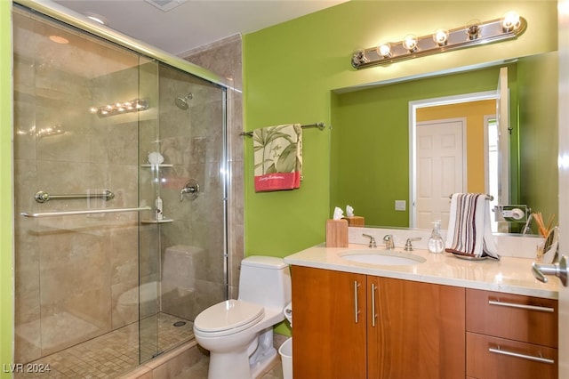 bathroom with vanity, toilet, and a shower with door