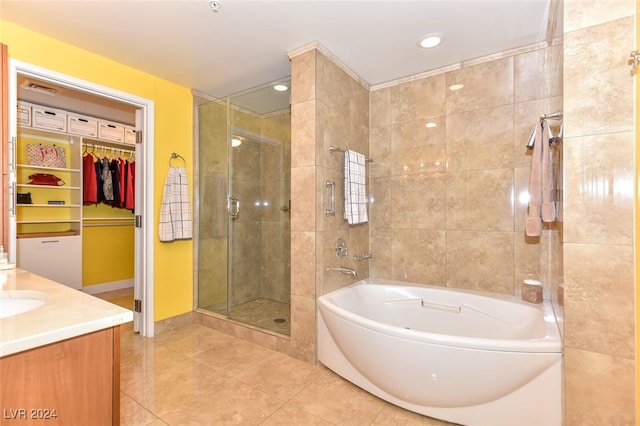 bathroom with a garden tub, a stall shower, a walk in closet, tile patterned floors, and vanity