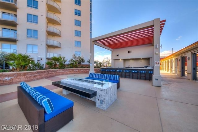 view of patio featuring an outdoor living space with a fire pit, an outdoor kitchen, and an outdoor bar