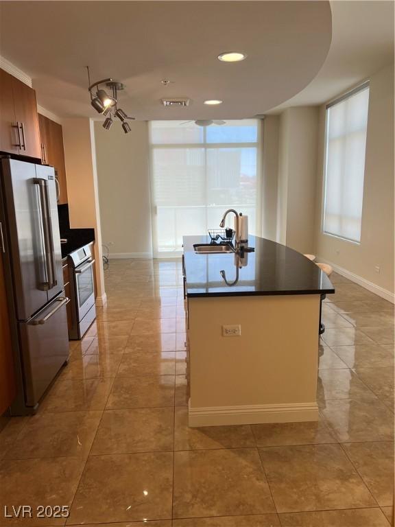 kitchen featuring a sink, dark countertops, light tile patterned floors, and appliances with stainless steel finishes