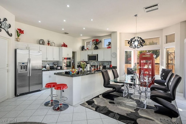 kitchen with white cabinets, backsplash, stainless steel appliances, and hanging light fixtures