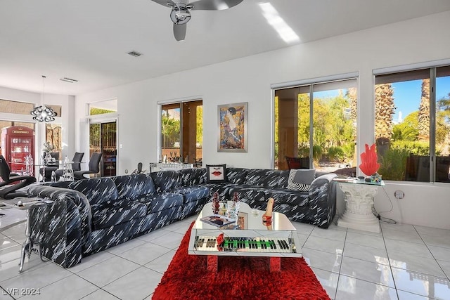 tiled living room with ceiling fan with notable chandelier