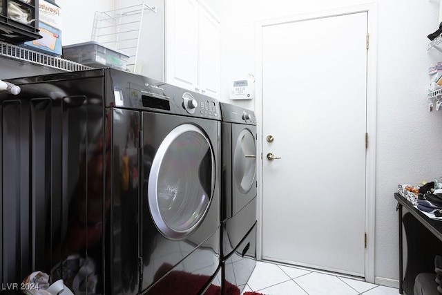 washroom with washer and clothes dryer, light tile patterned flooring, and cabinets