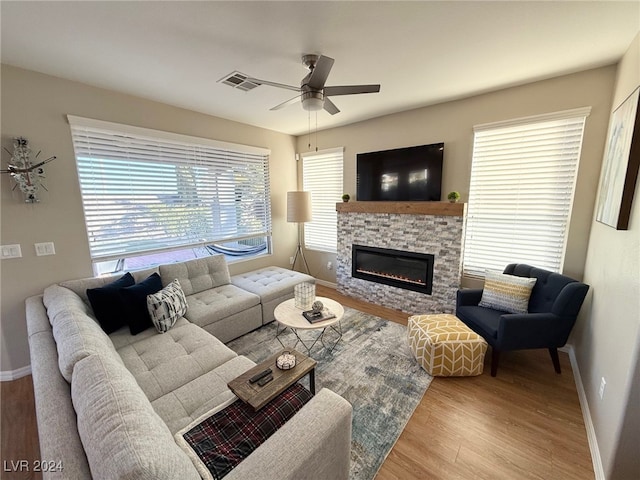 living room featuring a fireplace, light hardwood / wood-style flooring, a wealth of natural light, and ceiling fan