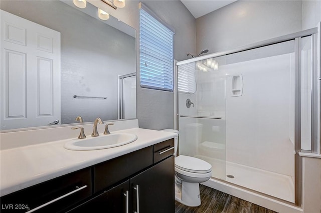 bathroom with wood-type flooring, vanity, toilet, and walk in shower