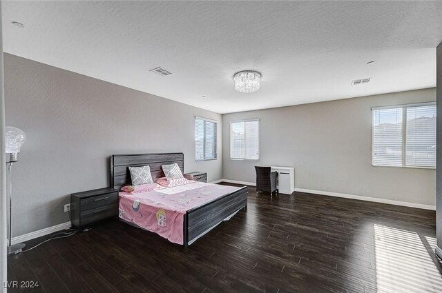 bedroom with a textured ceiling, an inviting chandelier, and dark wood-type flooring